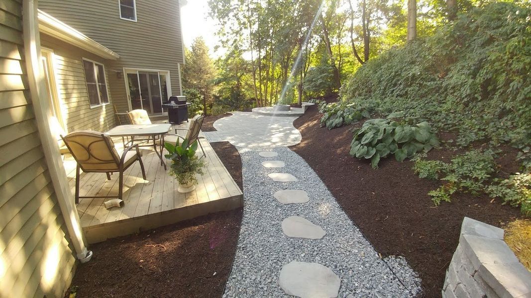 A walkway leading to a patio with a table and chairs.
