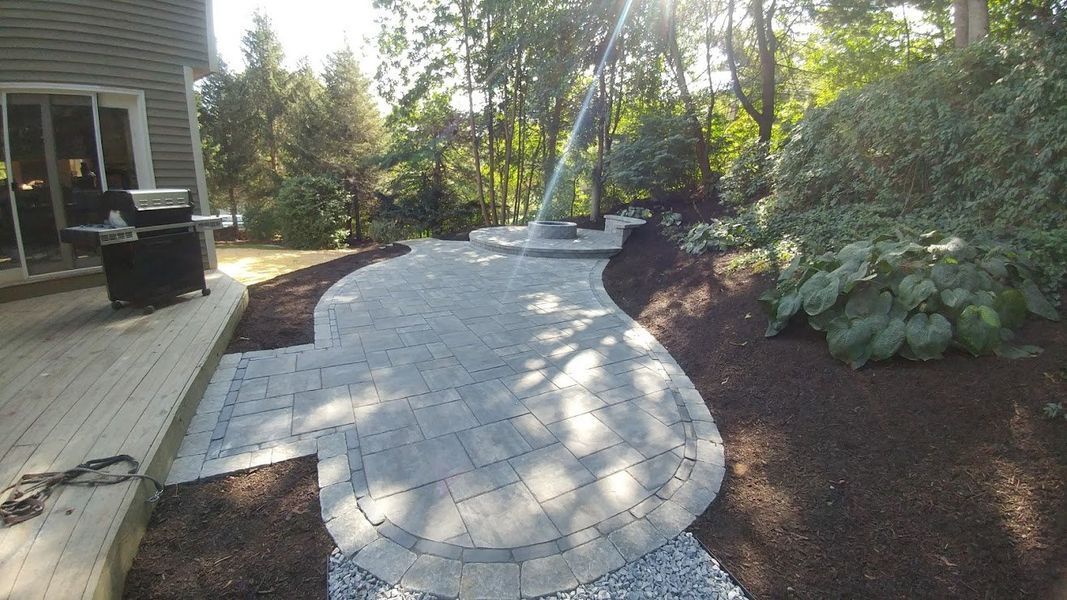 A walkway leading to a deck in a backyard surrounded by trees.