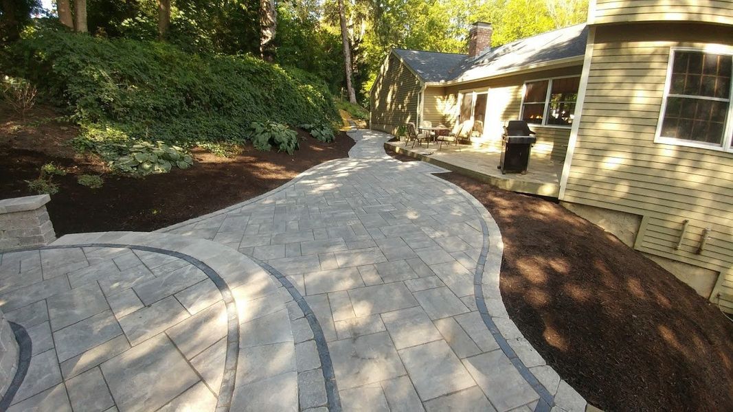 A brick walkway leading to a house in the woods.