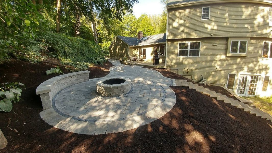 A fire pit is sitting in the middle of a patio in front of a house.