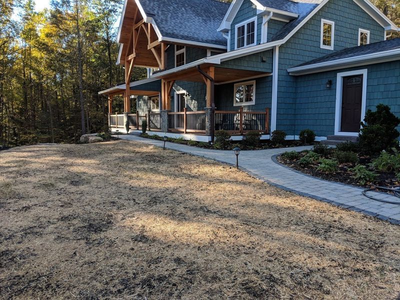 A large blue house with a porch and a walkway in front of it.