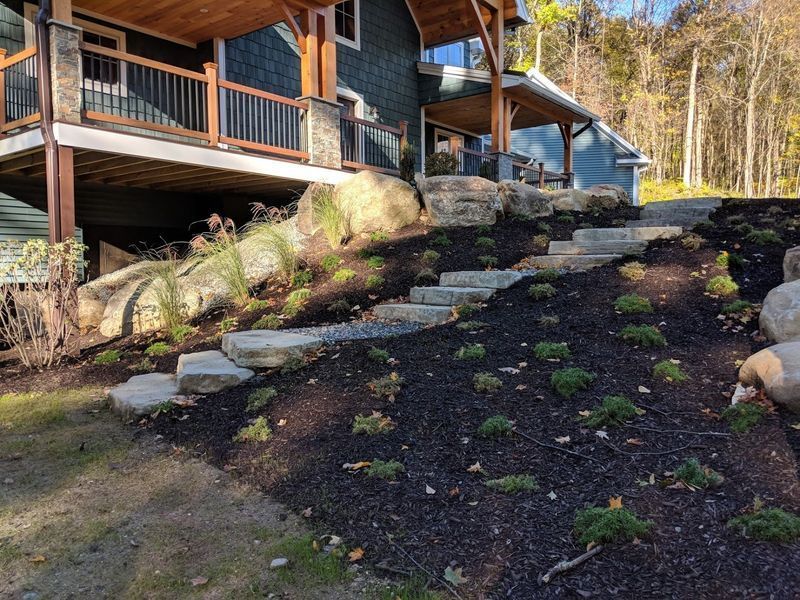 A house is sitting on top of a hill with stairs leading up to it.