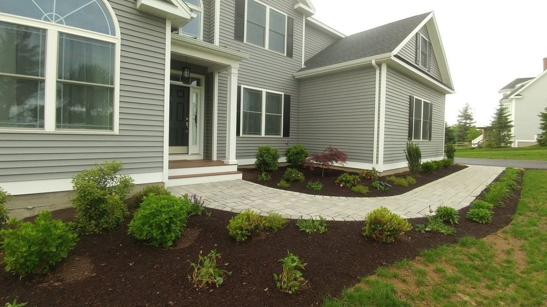 A large gray house with a walkway leading to the front door.