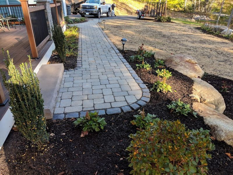 A white truck is parked on the side of a brick walkway.