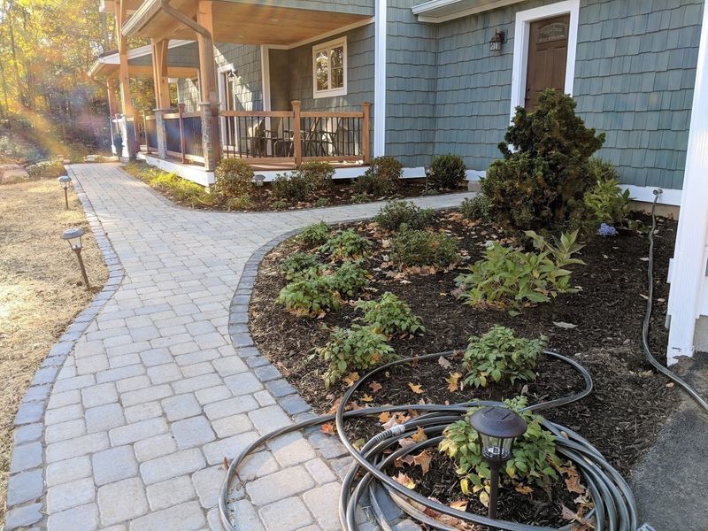 A hose is sitting on the sidewalk in front of a house