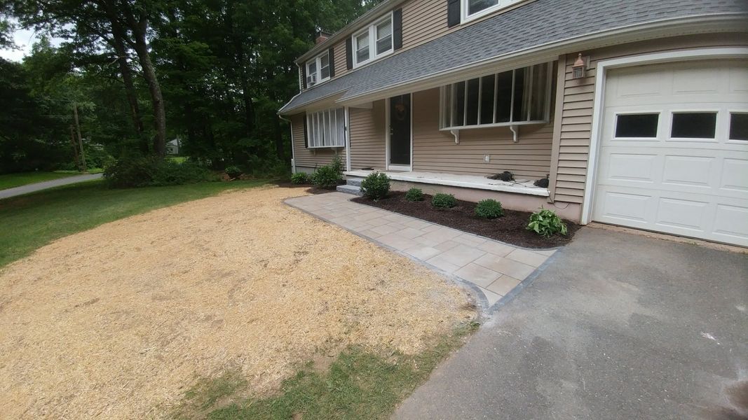 A house with a white garage door and a walkway in front of it.