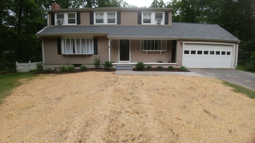 A house with a garage and a gravel driveway in front of it.