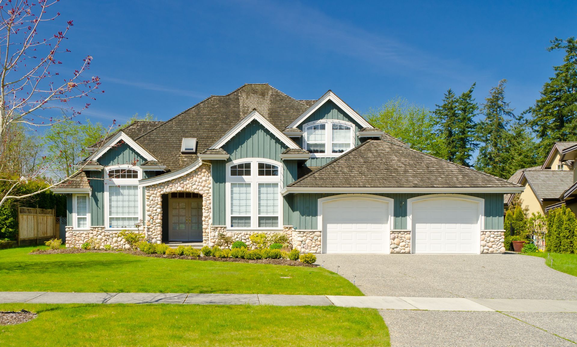 A large house with a slate roof and two garages