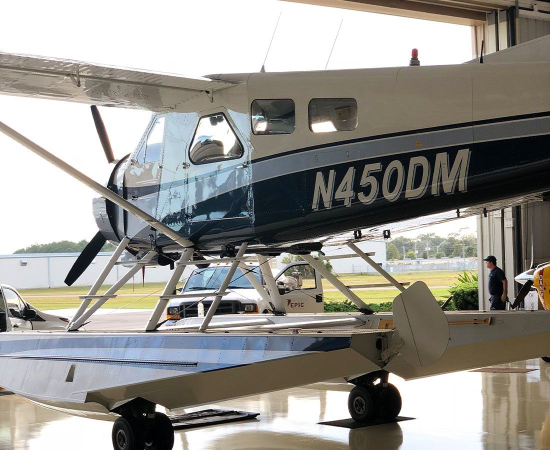 A small plane is parked in a hangar with the door open.