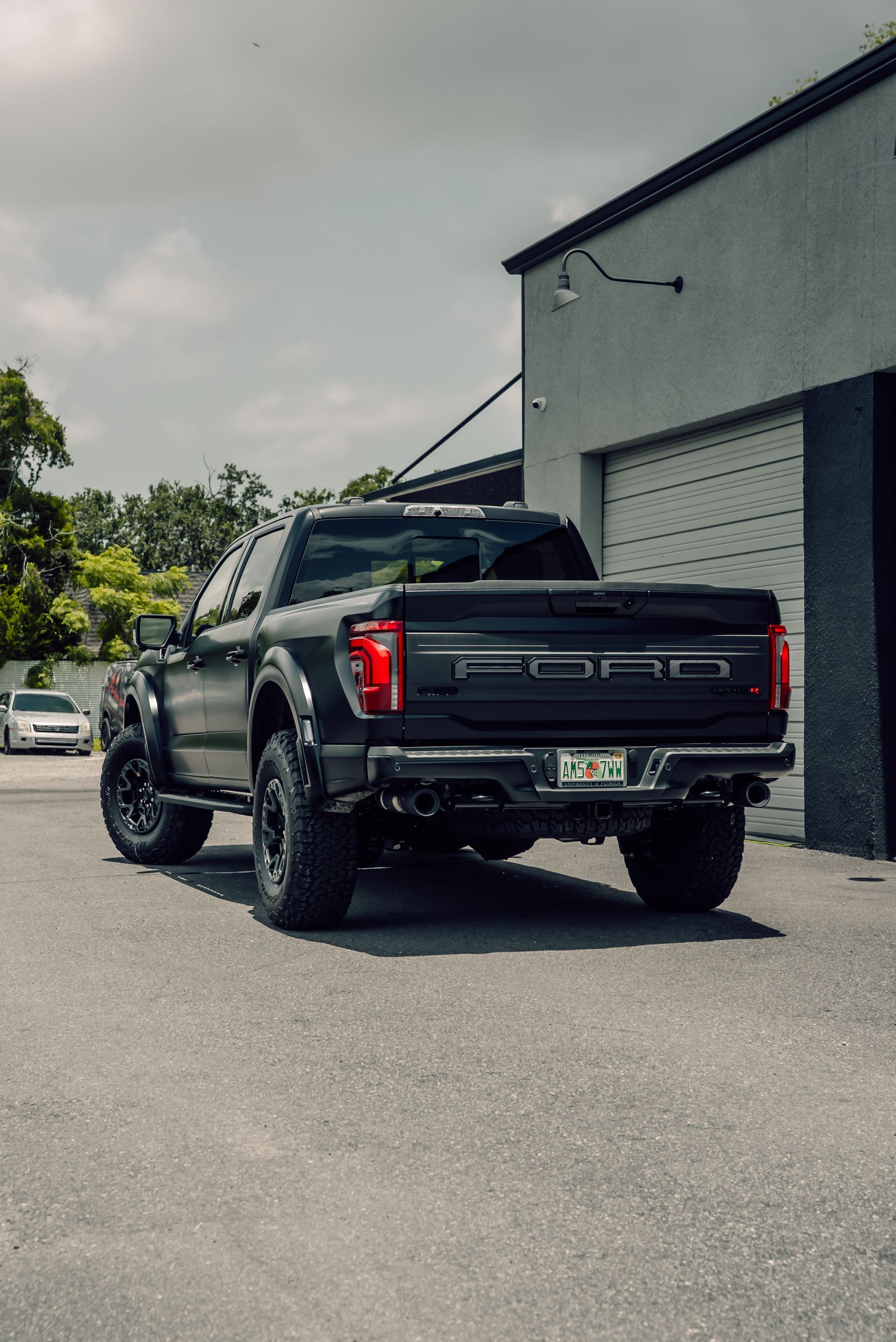 Black Ford pickup truck parked on asphalt next to a gray building.