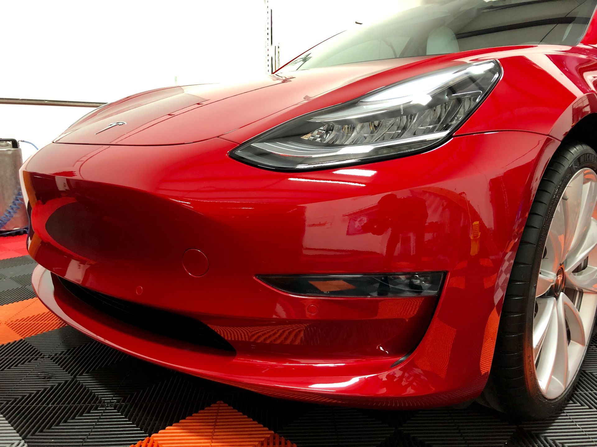 A luxury car reflecting a mirror-like gloss finish after ceramic coating application.