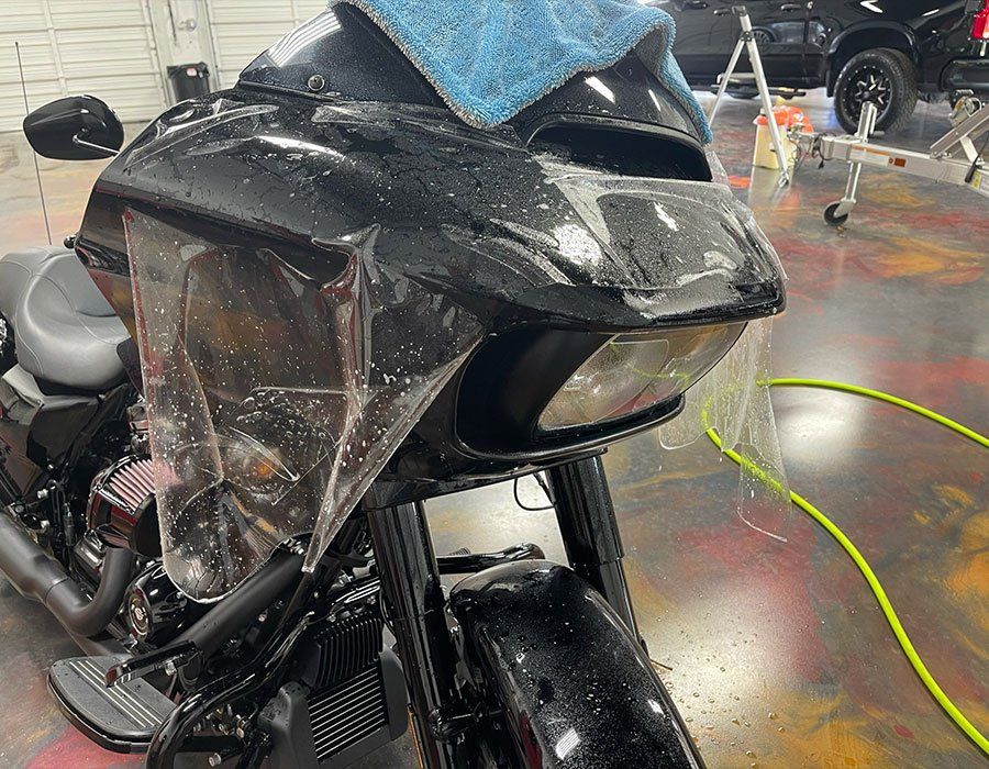 A black motorcycle with a protective film on the front is sitting in a garage.