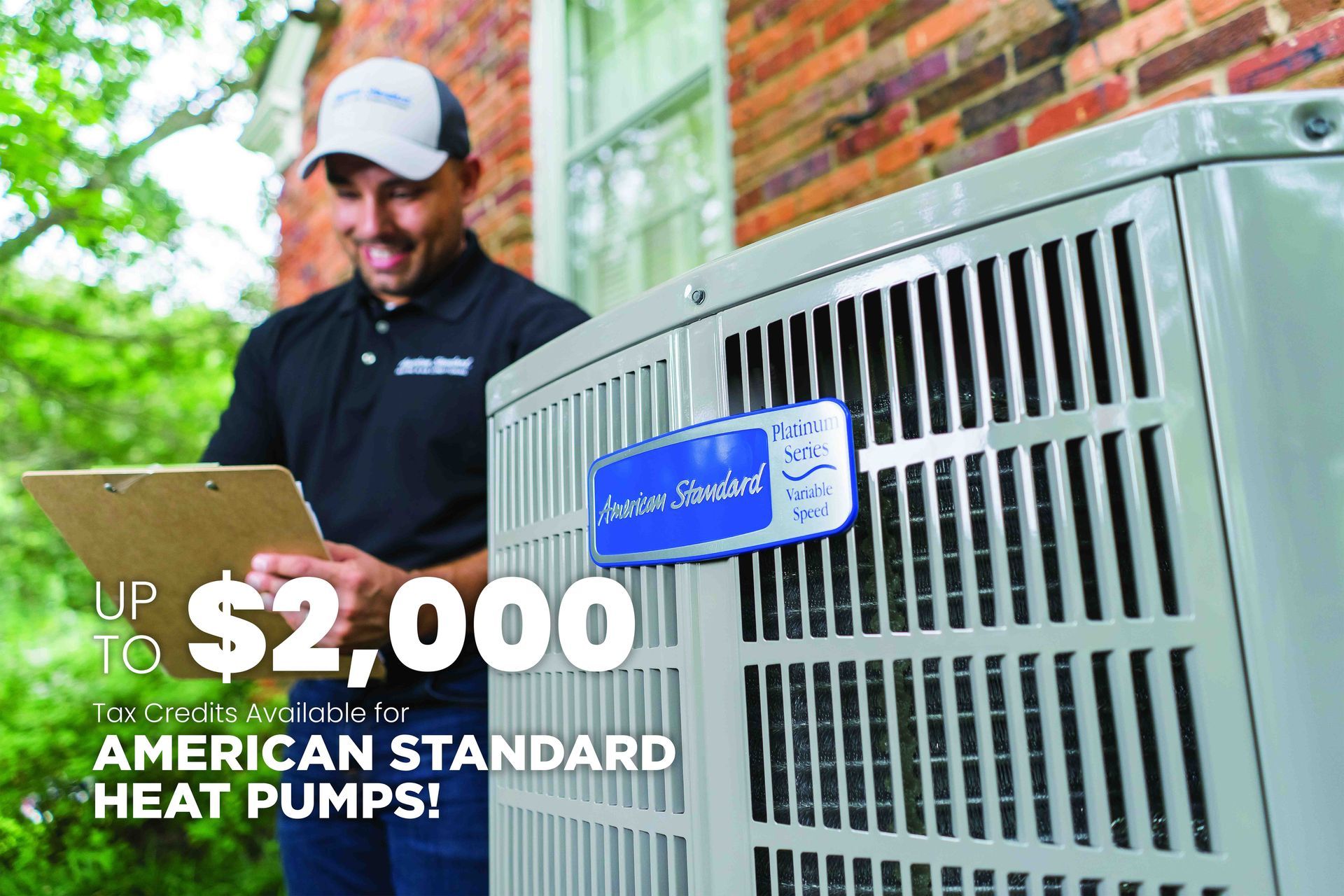 A man is standing next to an american standard heat pump holding a clipboard.
