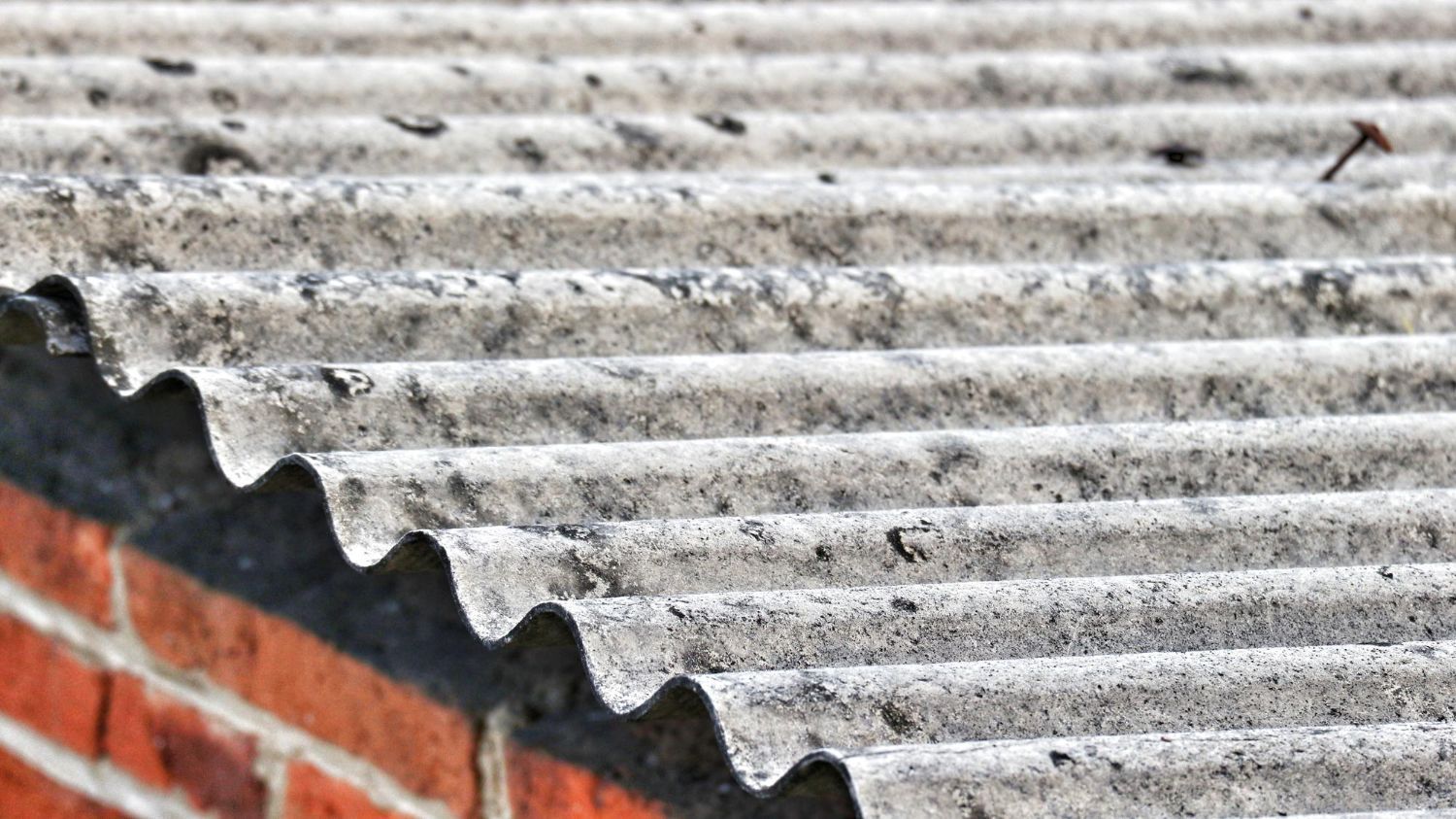 A close up of a roof with a brick wall in the background.