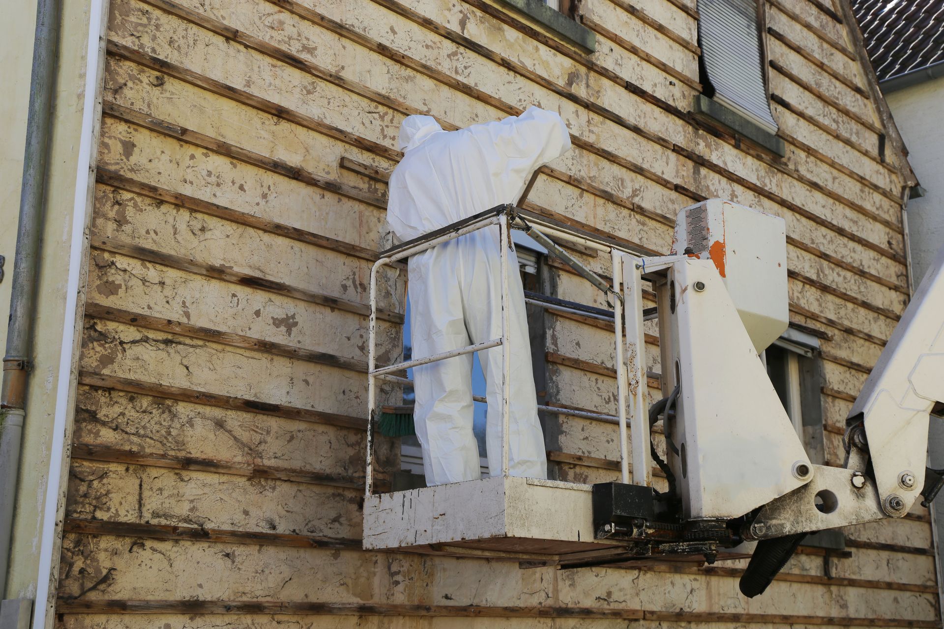 A man in a protective suit is working on a building.