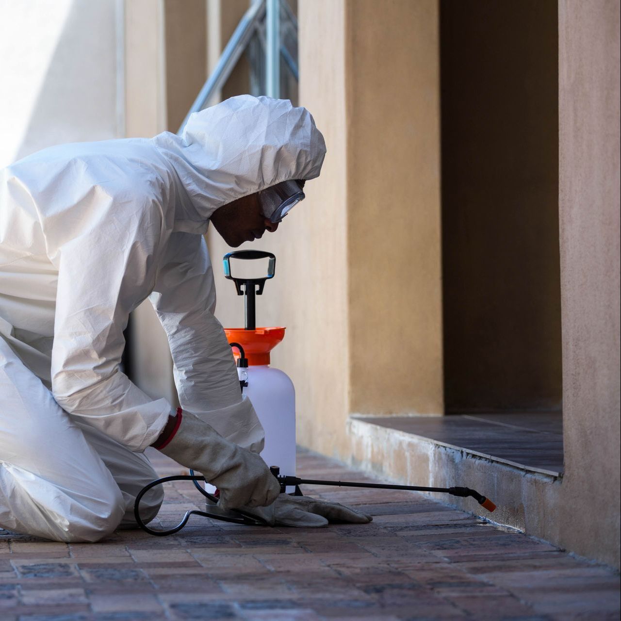 a man in a protective suit is kneeling down on the ground .