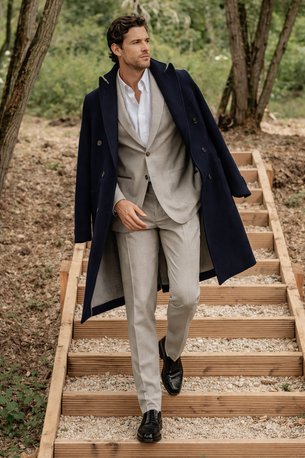 Un uomo in giacca e cappotto blu scuro scende le scale di legno all'esterno.