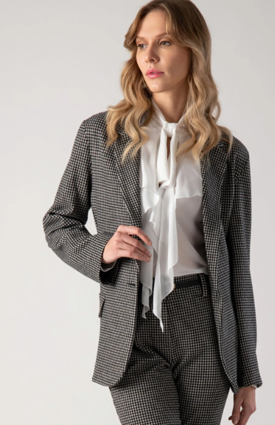 Donna con giacca e pantaloni a quadri bianchi e neri, camicetta bianca e papillon.