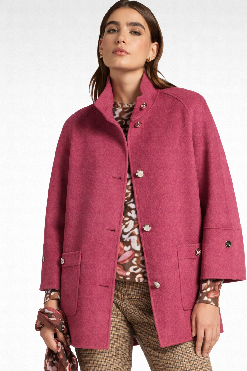 Donna con cappotto magenta e top fantasia, in piedi all'aperto.