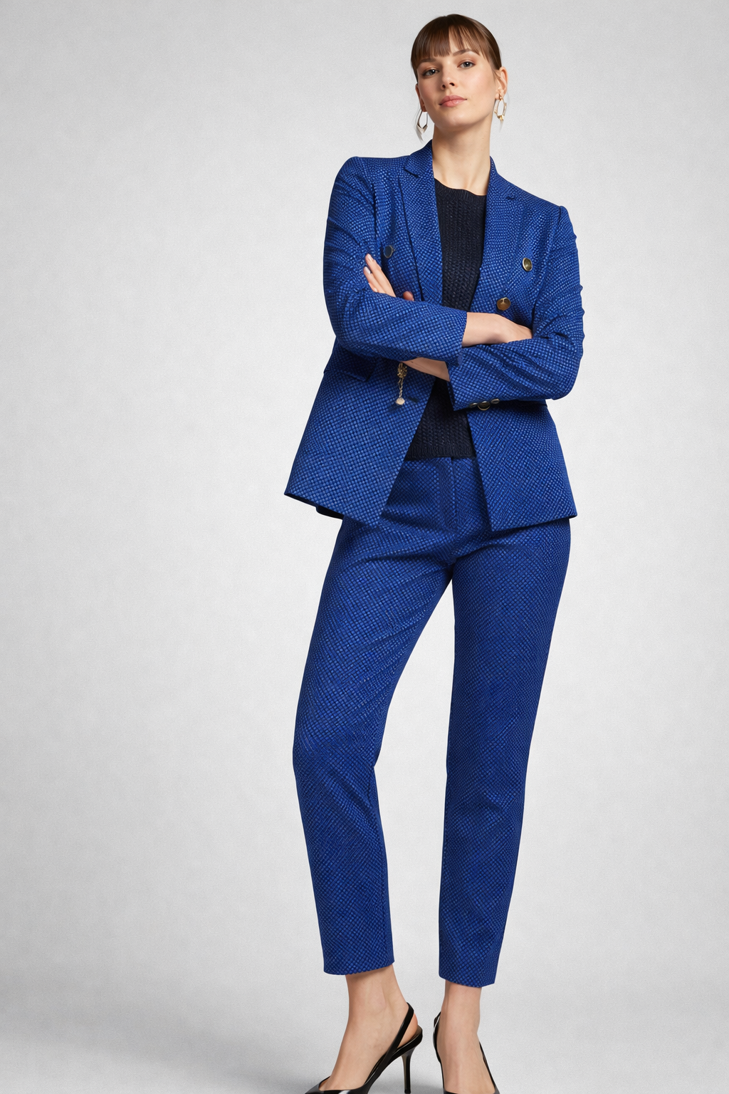 Donna in abito blu fantasia con braccia incrociate.