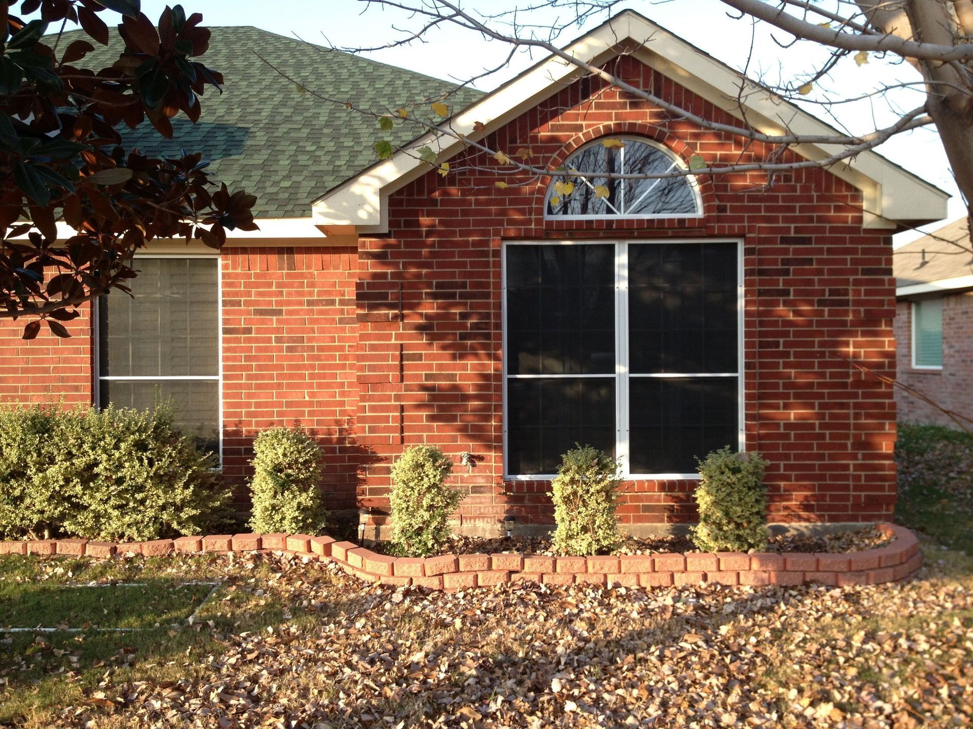 A red brick house with a screened in window