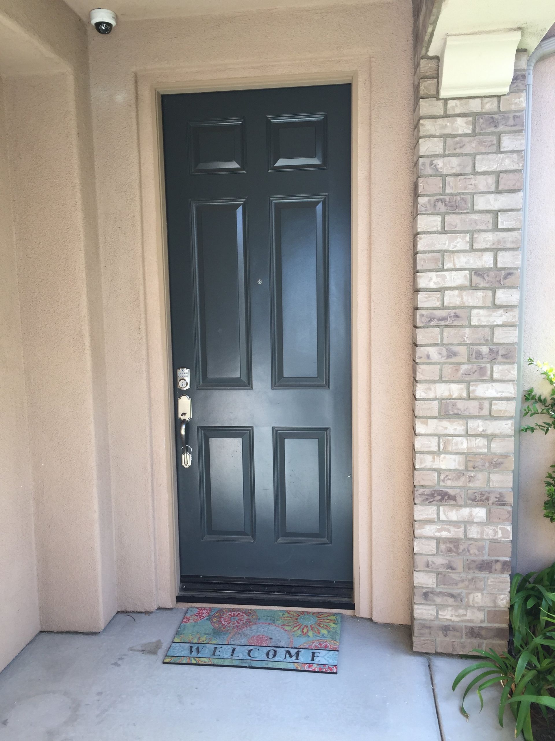 A black door with a welcome mat in front of it