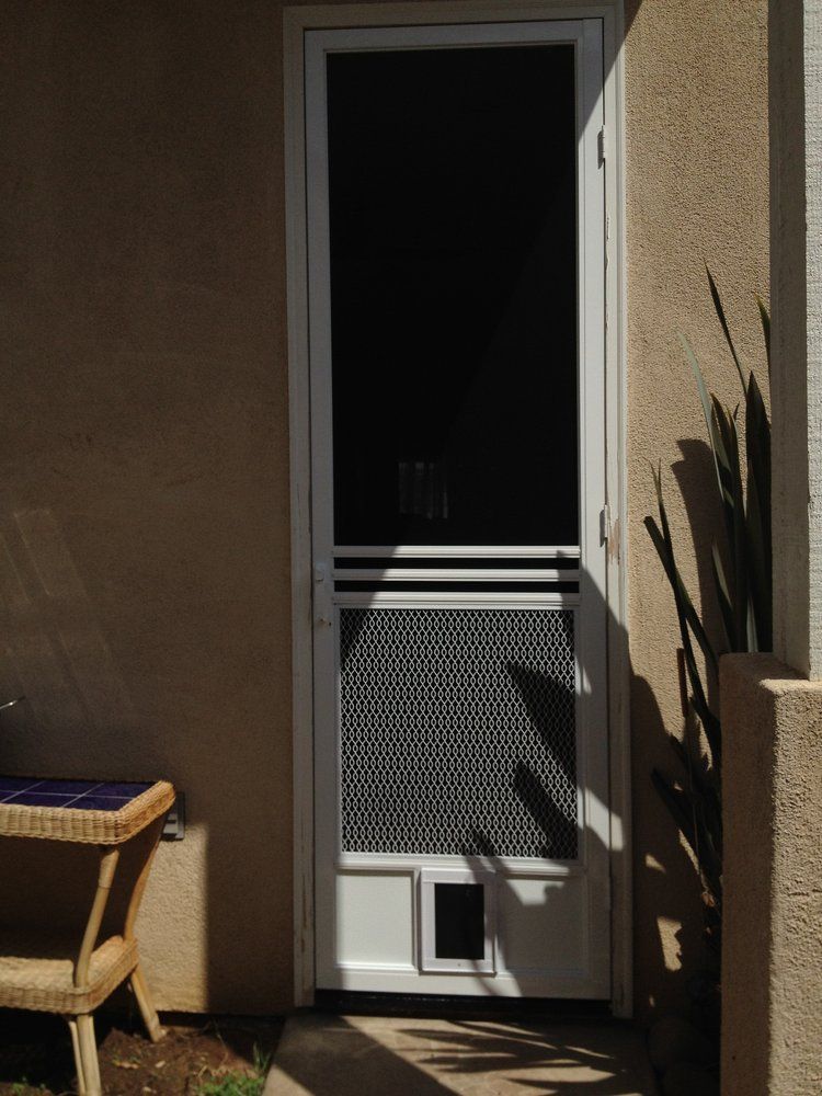 A white screen door with a cat door in it