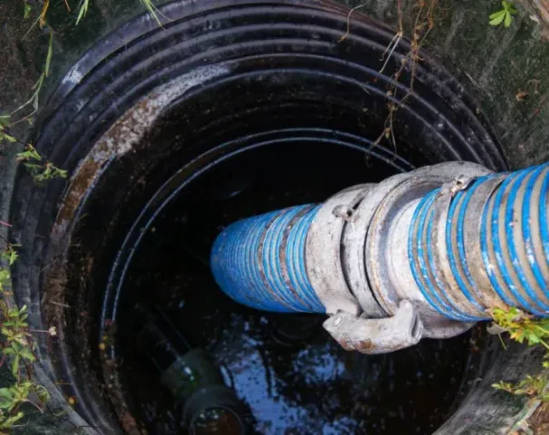 a blue hose is coming out of a manhole cover