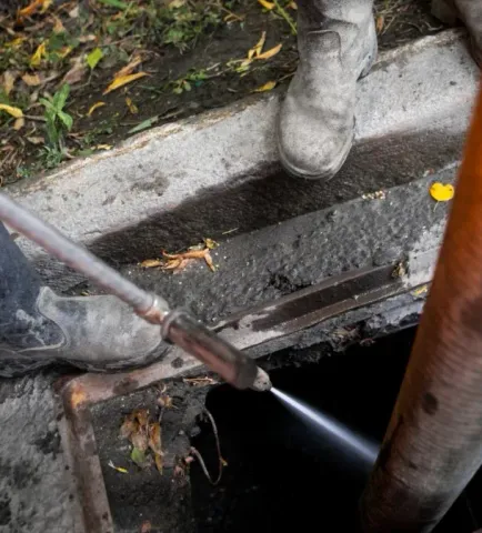 a person is using a high pressure hose to clean a drain