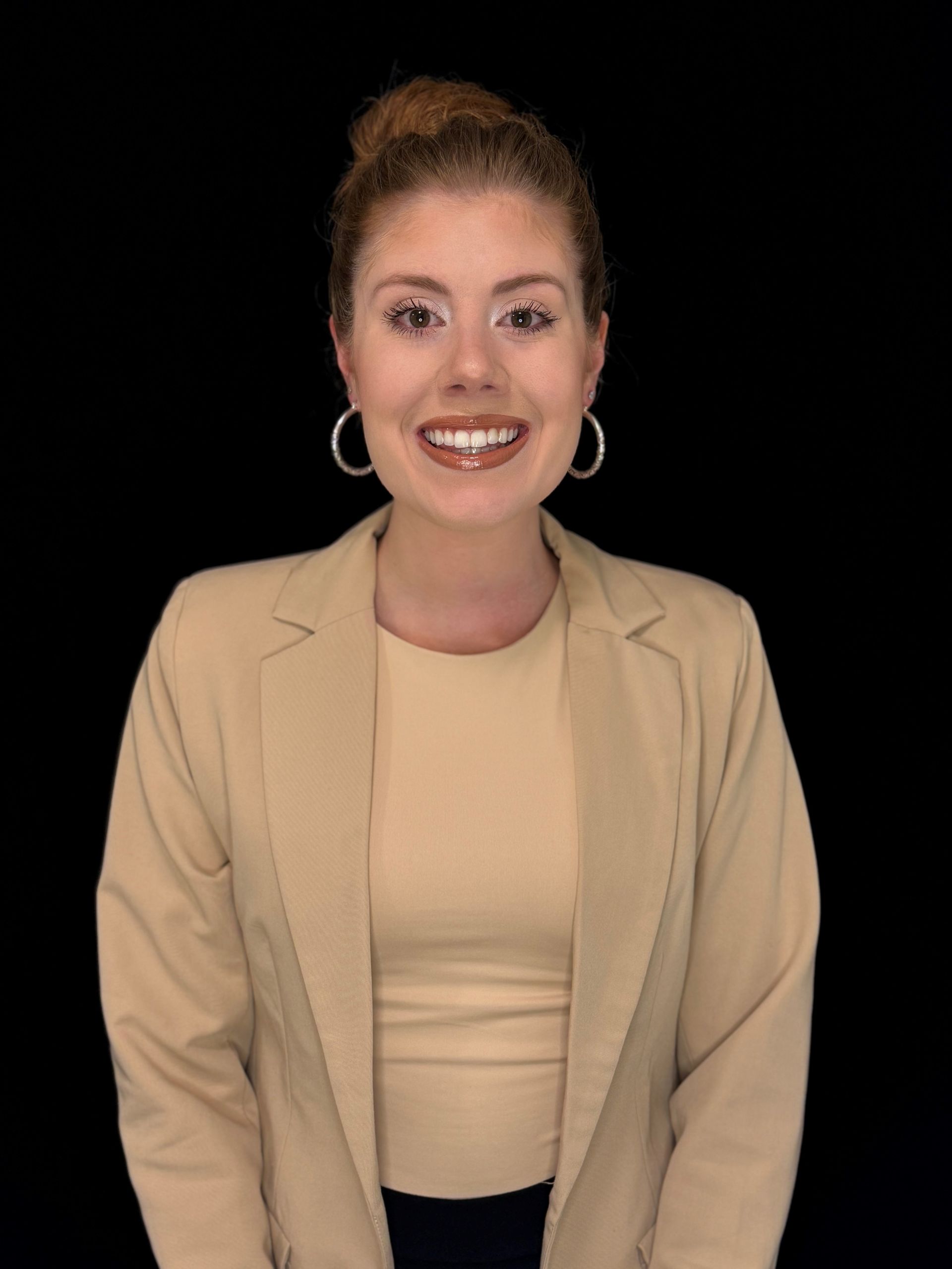 A woman wearing a tan jacket and earrings is smiling for the camera. Liz Bentley, summer law clerk at SRNM.
