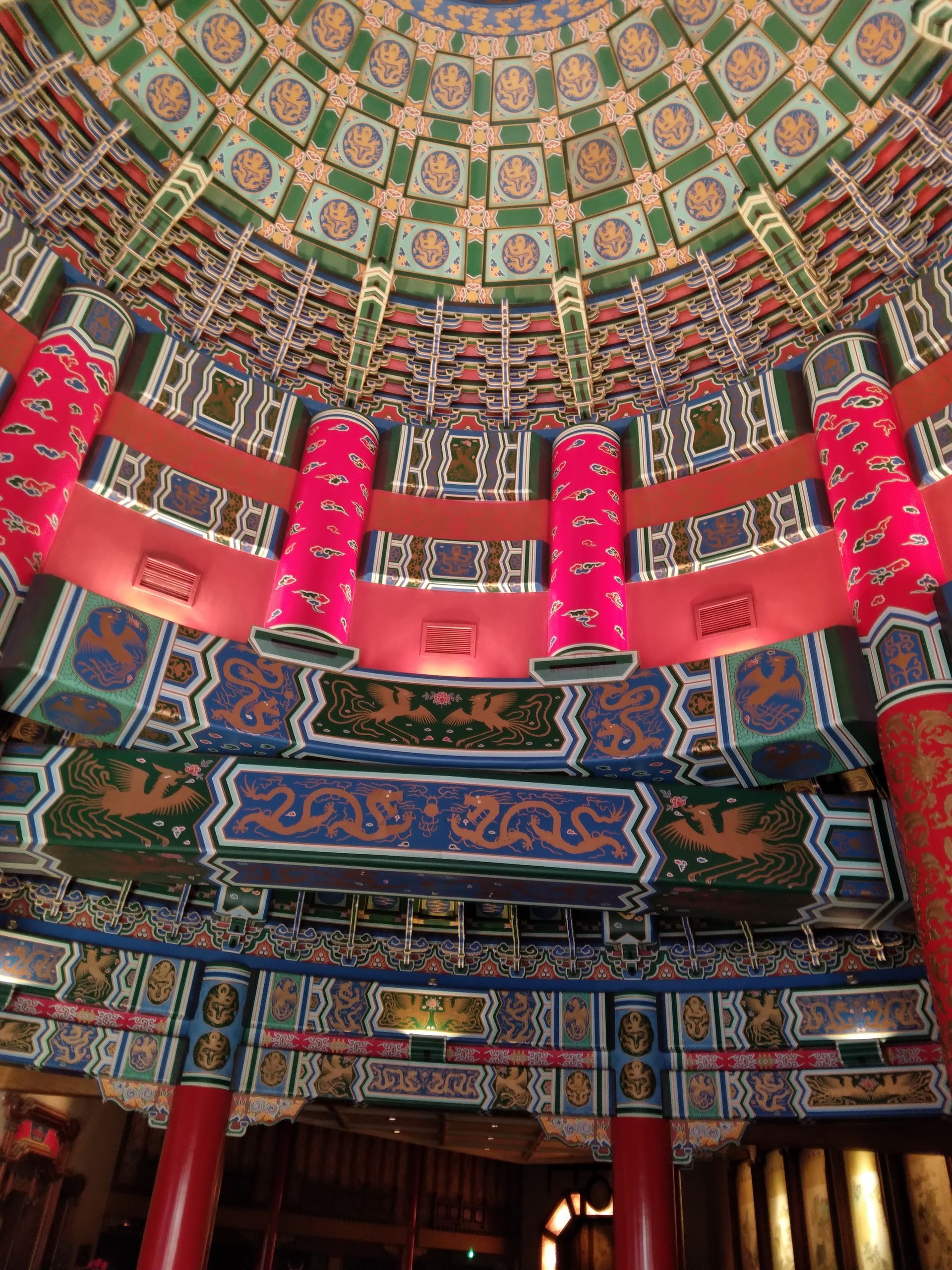 Ornate circular temple interior with colorful patterns, red lanterns, and decorated ceiling beams