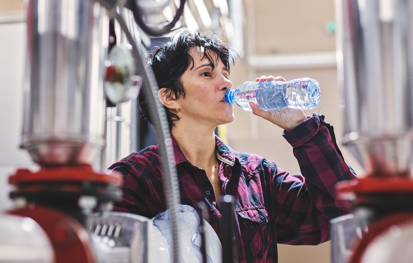 Female factory worker drinking water to hydrate
