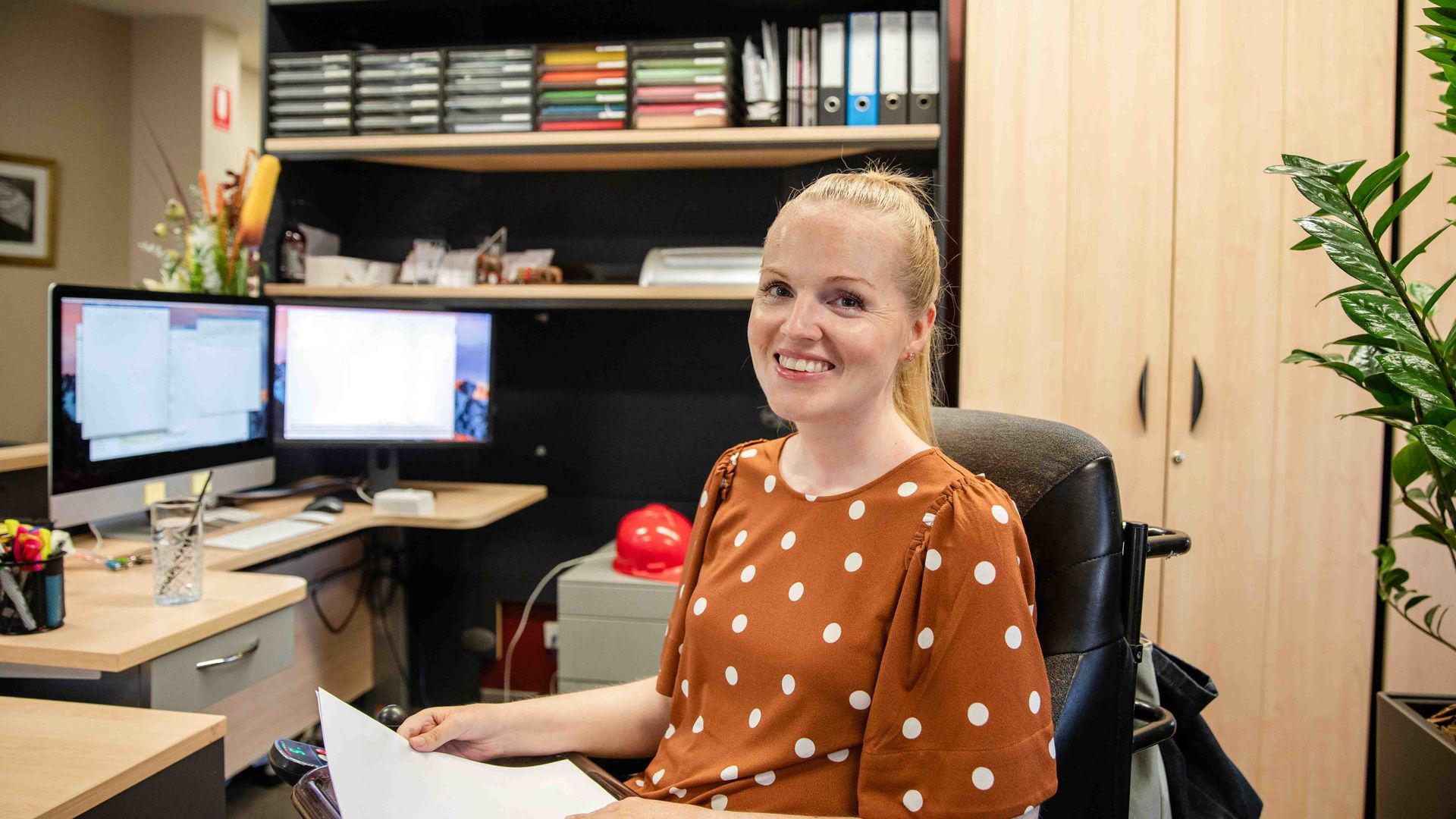 A woman with muscular distrophy sitting at a desk.