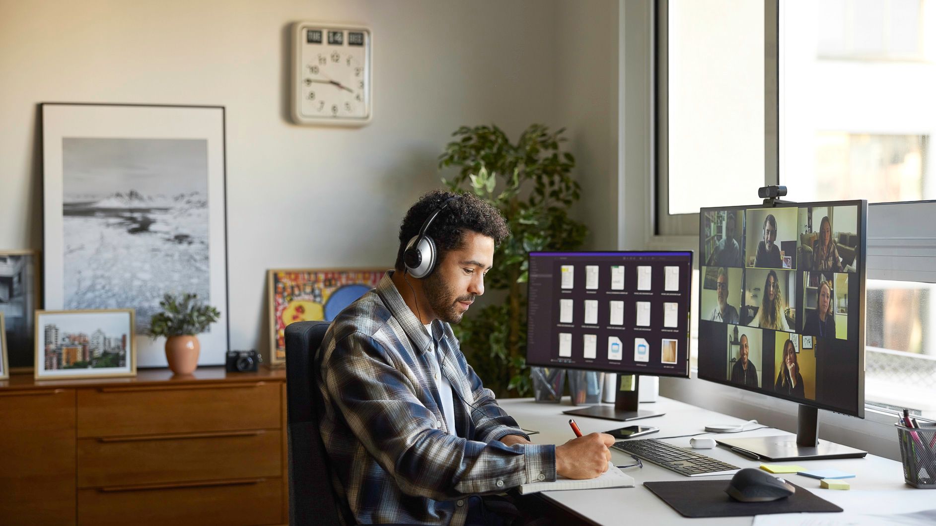 Man working at a desk with dual monitors in a bright home office