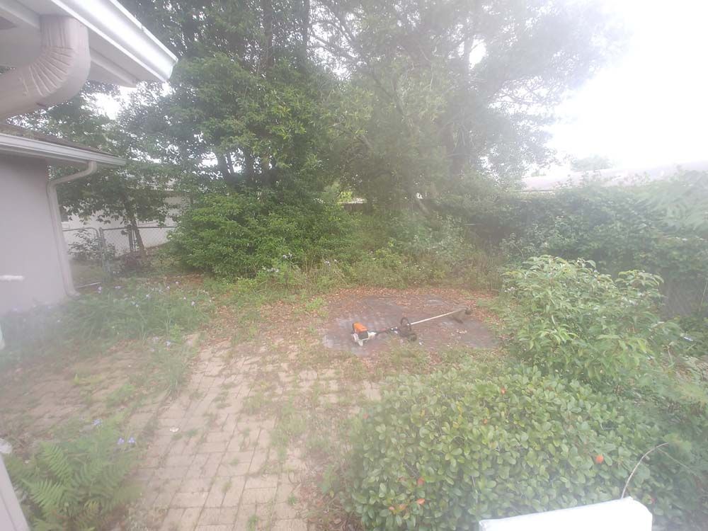 A backyard with a brick patio and trees in the background.