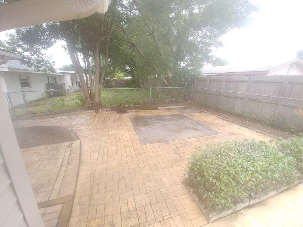 There is a brick patio in the backyard of a house.