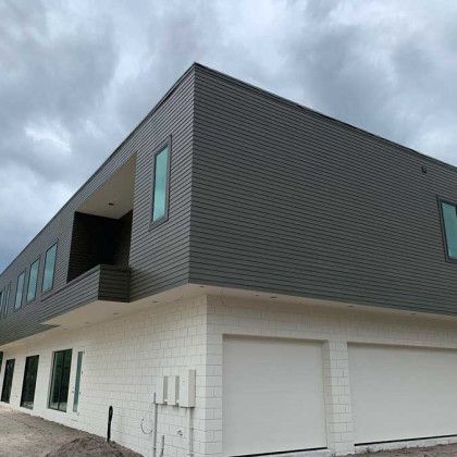 A large white brick building with a gray siding and white garage doors.