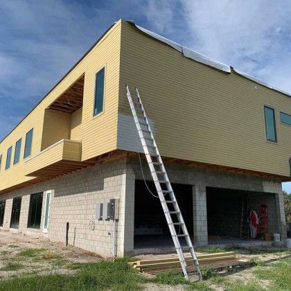 A large yellow building under construction with a ladder leaning against it.