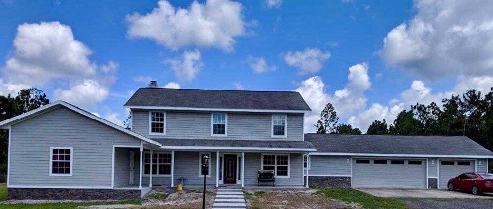 A large white house with a red car parked in front of it.