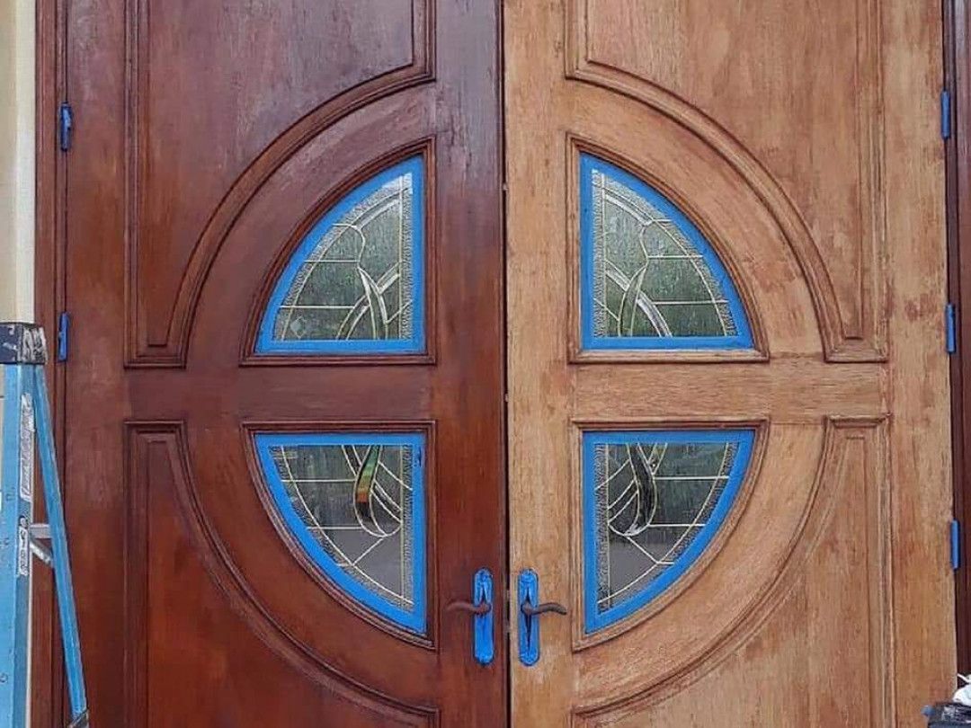 A wooden door with stained glass windows is being painted.