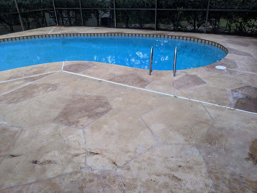 A large swimming pool is surrounded by a concrete deck.