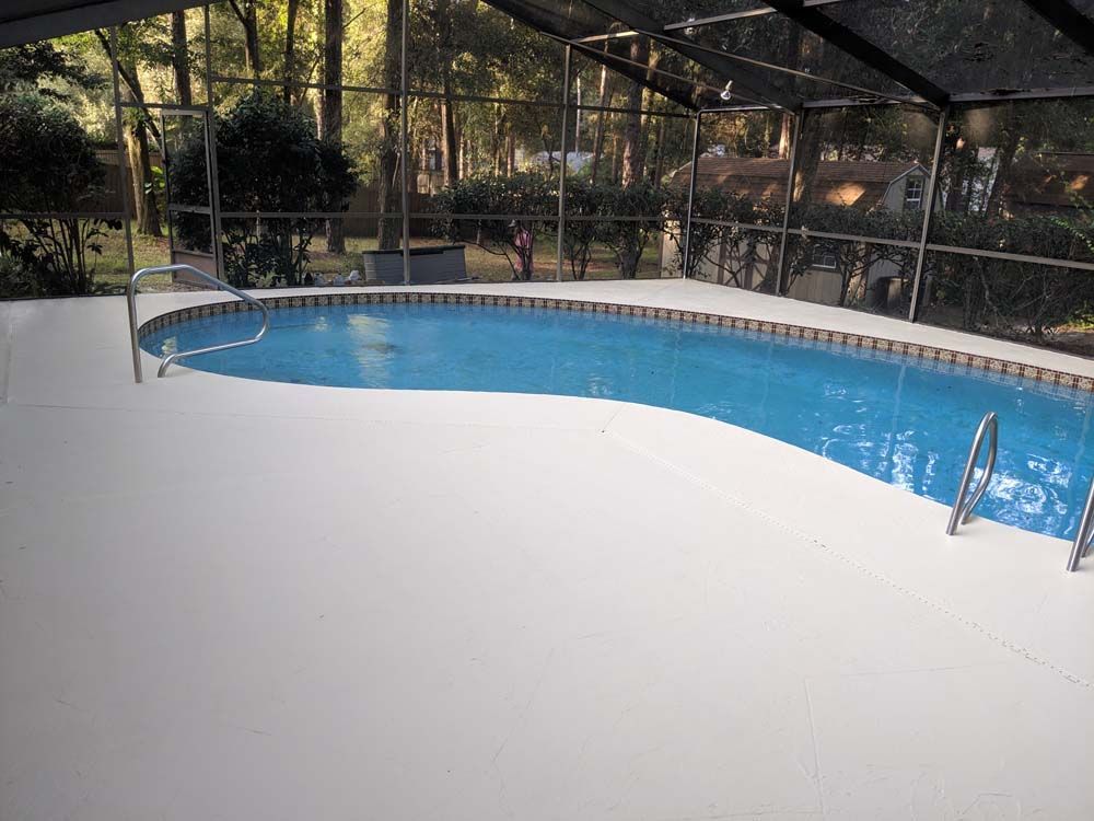 A large swimming pool is surrounded by a screened in area.