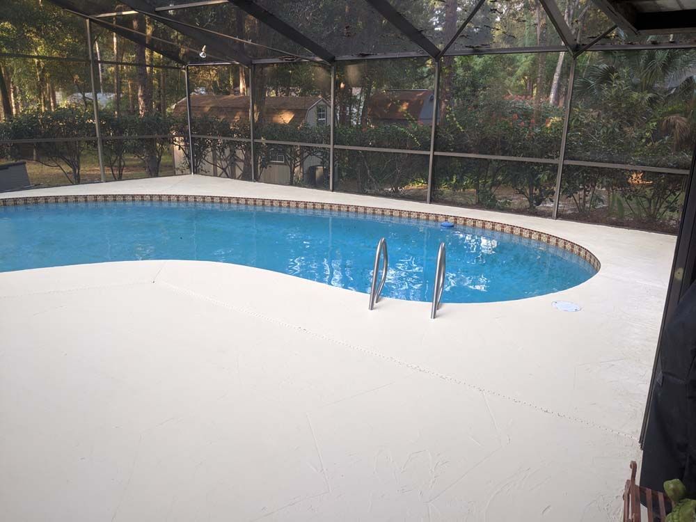 A large swimming pool is surrounded by a screened in area.