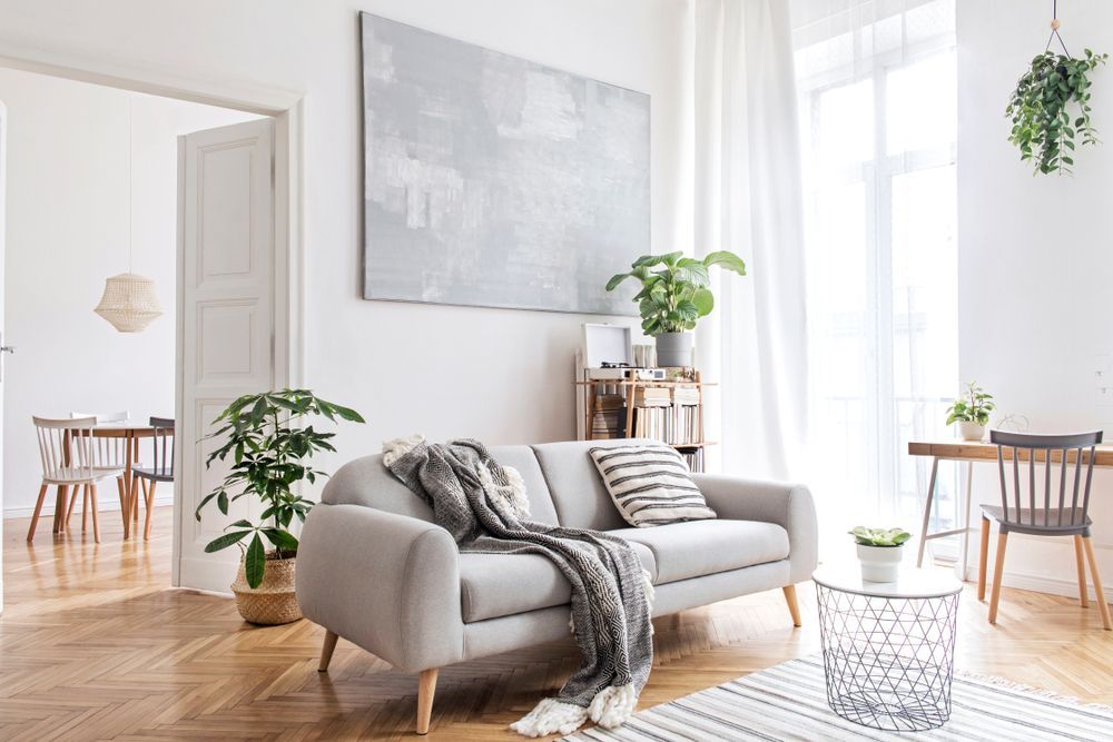 A living room with a couch , table , chairs and a painting on the wall.