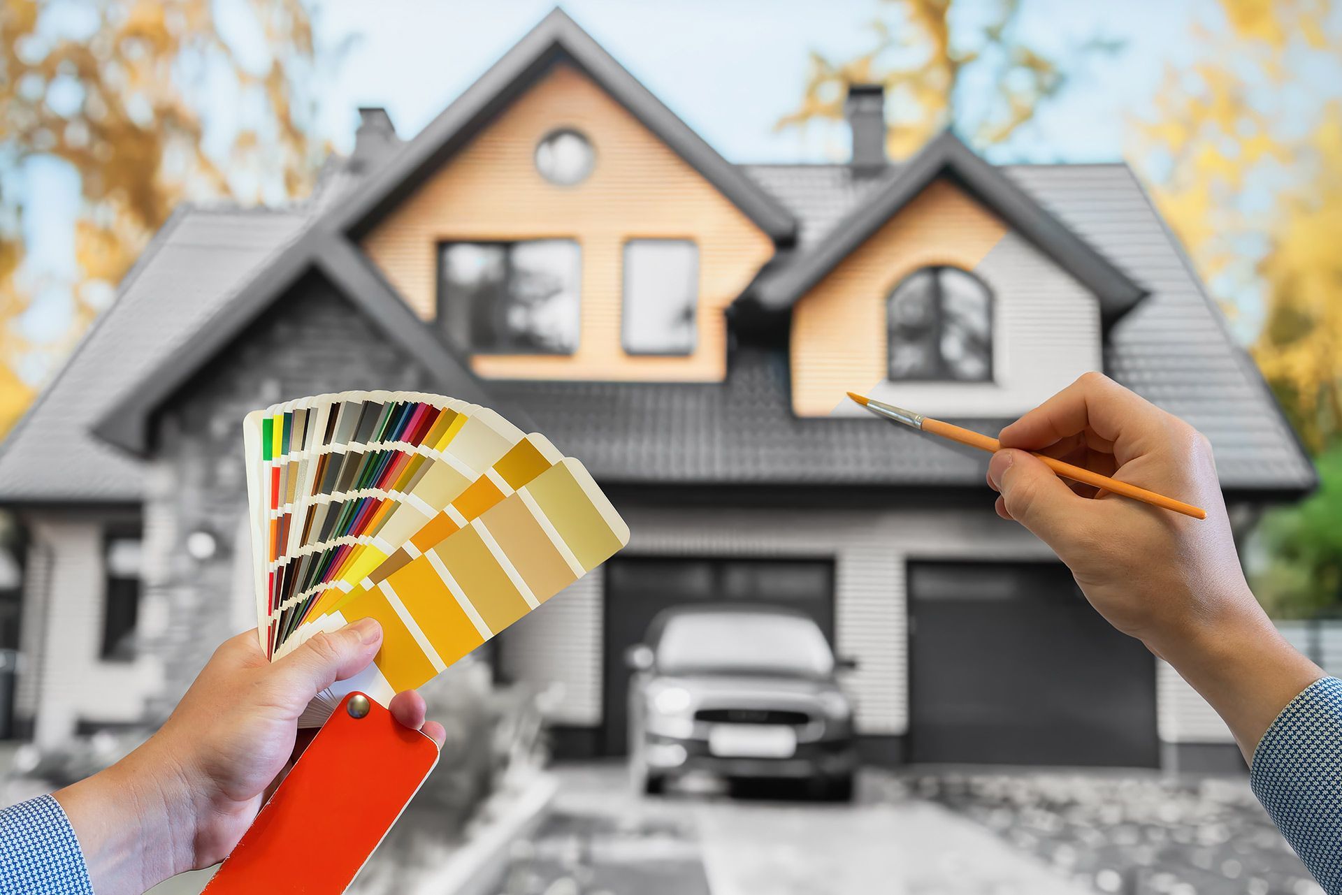 A person is holding a palette of colors and a brush in front of a house.