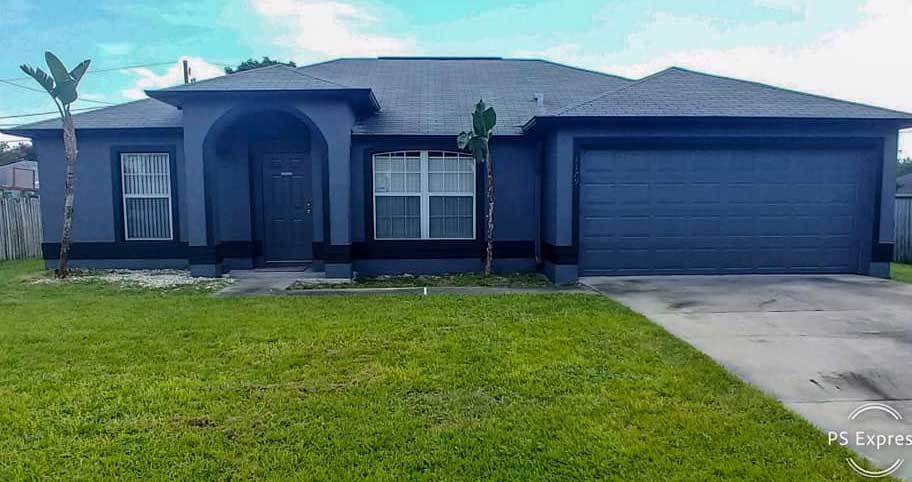 A black house with a lush green lawn in front of it.