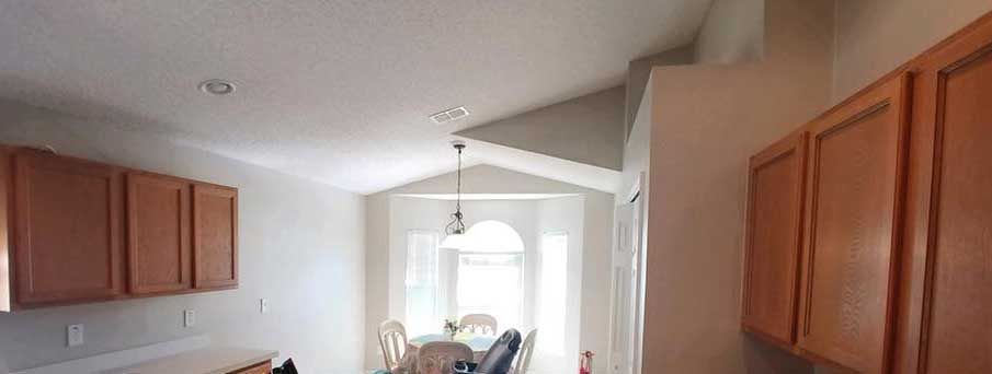 A kitchen with wooden cabinets and a dining room with a table and chairs.