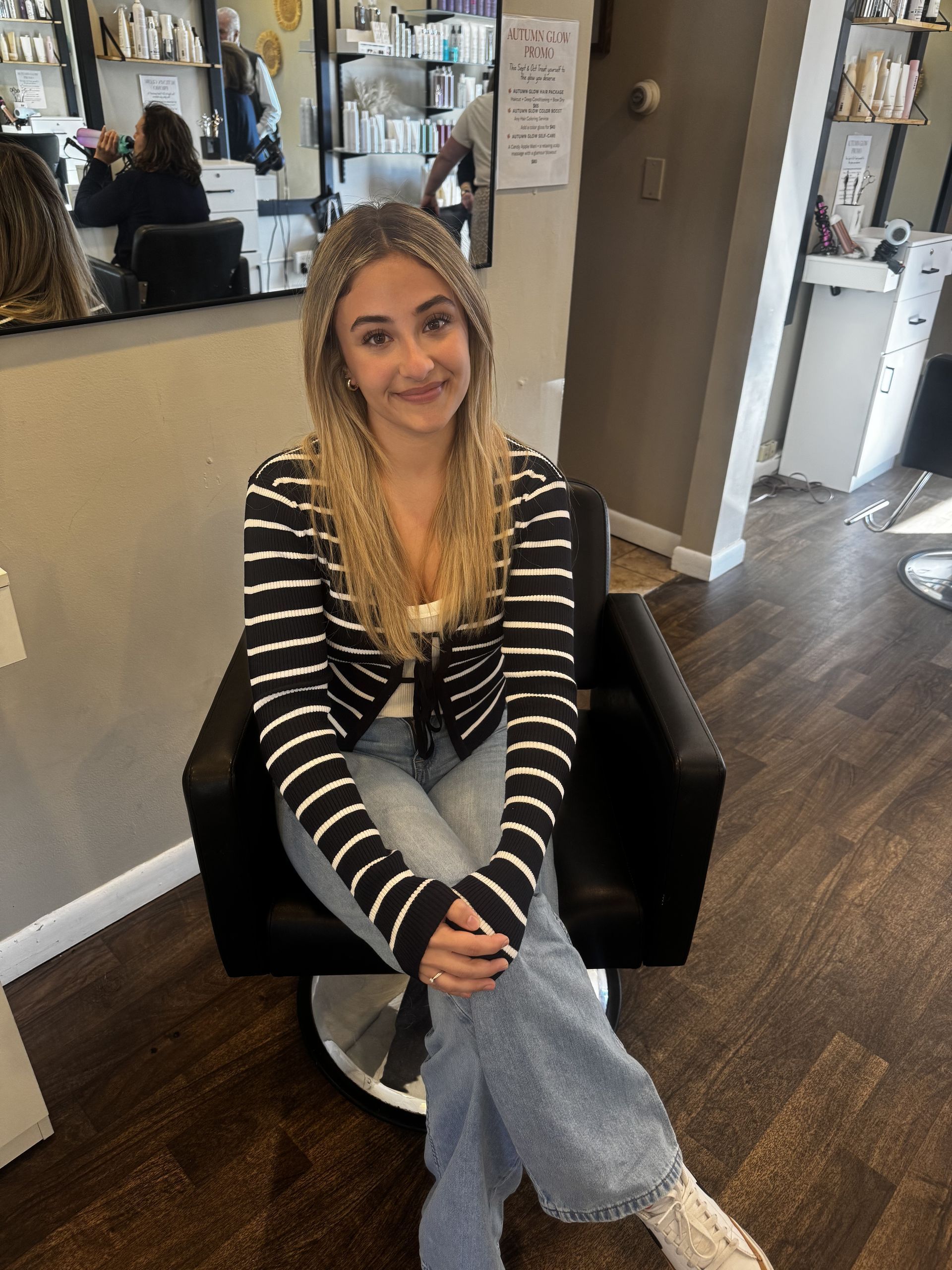 A woman wearing a hat is sitting in a chair in front of a mirror.