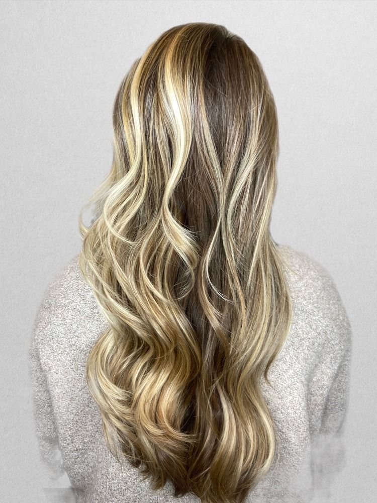 A woman with long blonde hair is wearing a grey sweater.