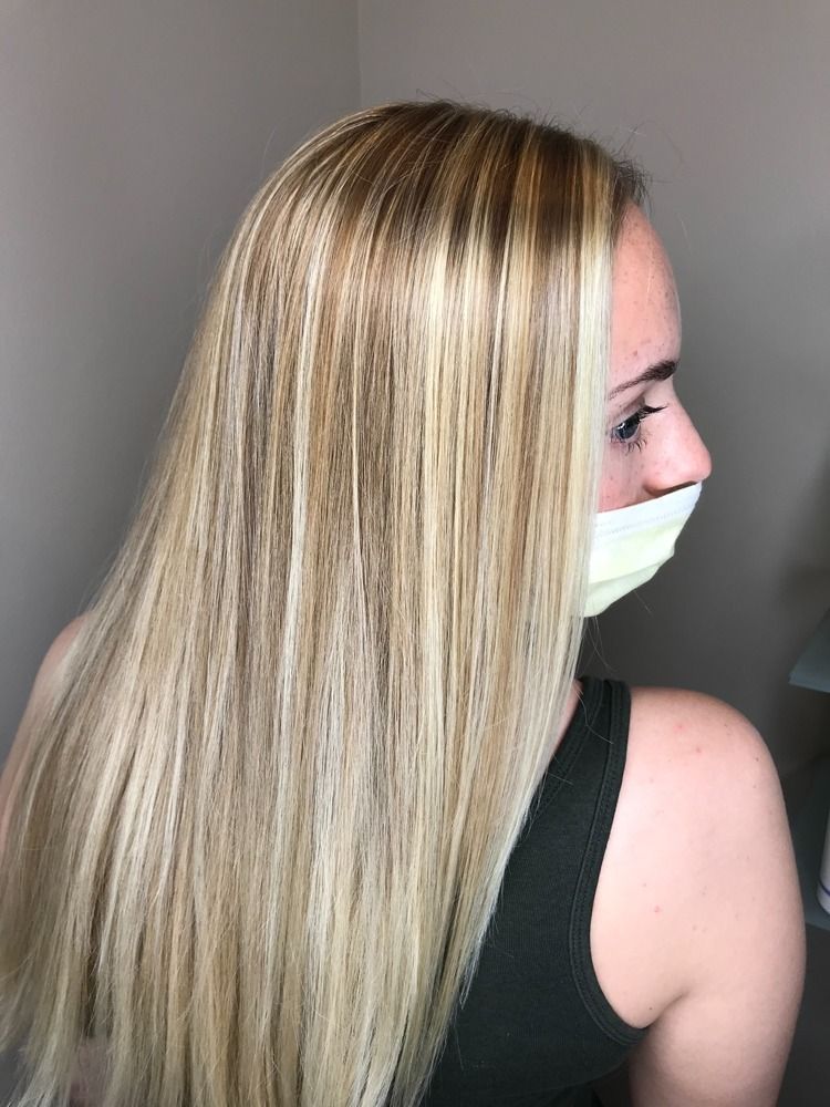 A woman with long blonde hair is wearing a mask.